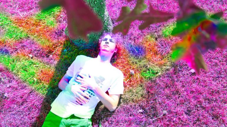 Jeune homme allongé sur l'hebe avec des couleurs psychédéliques - crédit photo : HandintheBoxinc via Shutterstock